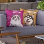 Two red and light brown pet loss cushions with cat and dog photos and halo, placed on a couch
