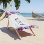 Personalized beach towel with name for her, featuring a floral design, draped over a beach chair