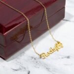 Custom pet name necklace in gold finish placed elegantly on a table, showcasing the pet's name and the paw charm
