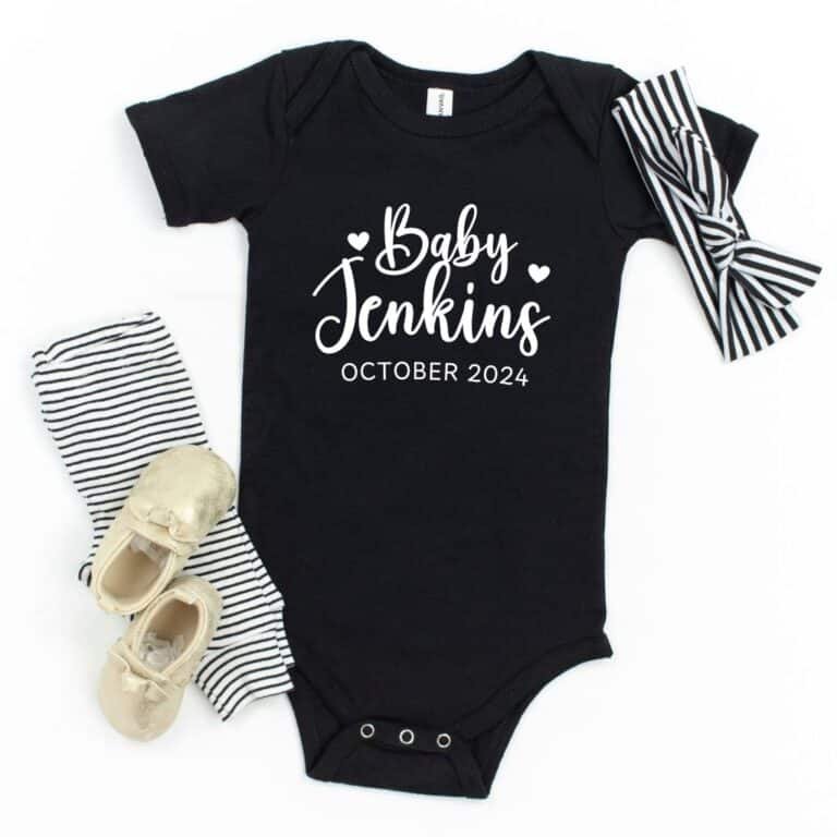 Black short-sleeve baby romper used for pregnancy announcements, suitable for baby girl or boy, featuring a cute printed message