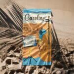 Custom name beach towel for music lovers, flat laid on the sand at the beach, featuring musical notes and personalized text – perfect summer gift