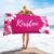 Custom towel with name in medium red violet, featuring floral design — perfect beach gift for her, laid out near the shore