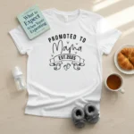 White Promoted to Mama Est custom year t-shirt displayed flat lay with baby book, baby shoes, bottle and coffee, personalized first time mom gift